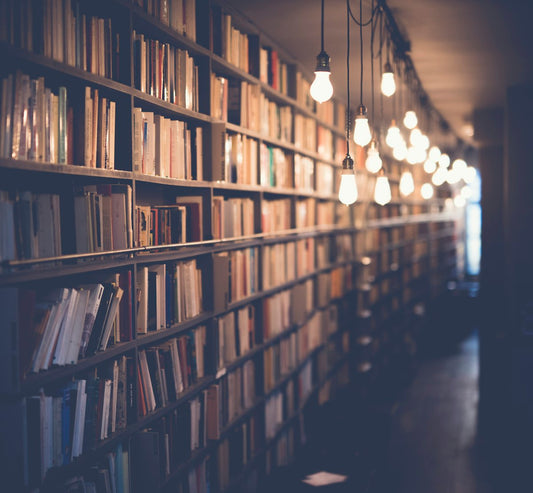 Ancient library with towering bookshelves in dramatic shadow